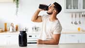Young,Arab,Guy,Drinking,Protein,Shake,From,Bottle,At,Kitchen,