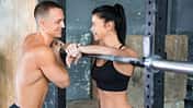 Sportliche Frau flirtet im Gym mit einem durchtrainierten Mann
