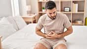 Darmbeschwerden Mann hält sich den Bauch vor Schmerzen.