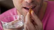Mann schluckt ein Omega-3-Supplement.