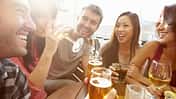 Freundesgruppe sitzt draußen und trinkt alkoholische Getränke.
