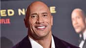 Dwayne Johnsons Gesicht vor dem Hintergrund eines Filmplakats. 