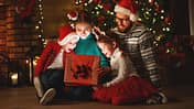 Familie schaut in ein Geschenk unter dem Tannenbaum.