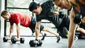 Group of friends doing pushups with dumbbells