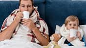 Ein Vater und sein Sohn liegen krank im Bett