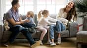 Mutter und Vater sitzen mit ihren zwei Kindern auf dem Sofa und albern herum