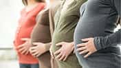 Vier schwangere Frauen, die ihre Hände auf den Bauch gelegt haben