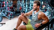 Mann lenkt sich auf einem Fitnessgerät mit dem Handy ab