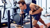 Superstar Jason Fox schiebt einen Gewichtsschlitten im Gym.