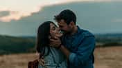 Traveling,Couple,Standing,Outdoors,Together,And,Laughing,During,An,Evening
