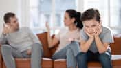 Man sieht im Vordergrund einen kleinen Jungen, der genervt guckt, im Hintergrund sitzen seine Mutter und sein Vater auf dem Sofa und diskutieren.