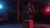 Muscular man trains jumping on a wooden box in a dark gym. Athlete Workout in red blue neon light. Cross, functional training