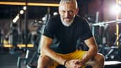 Sportsman with a happy smile sitting on the weight bench