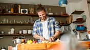 Young man preparing food at home, slicing bread