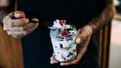 Ein Mann hält ein Glas mit Quark und gefrorenen Beeren