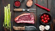 Rohes frisches marmoriertes Fleisch Black Angus Club Steak und Zutaten, auf altem dunklem Holztischhintergrund, Blick nach oben flach lagen