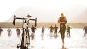 Triathleten laufen durch das Wasser zu ihren Fahrrädern