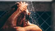 Engrossed in his grooming ritual, a man rinses his hair, the water's embrace enhancing the meditative quality of his daily routine.