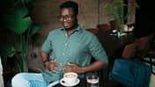 Mann trinkt Kaffee und hält sich den schmerzenden Bauch