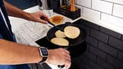 Mann brät Pancakes in der Pfanne