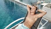 Junger Mann genießt ein Hörbuch am Pool