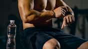 Beschnittenes Porträt eines jungen sportlichen Mannes, der die Herzfrequenz auf der Uhr überprüft