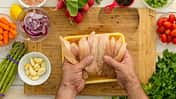Geflügelfleisch auf einem Holzbrett, Gemüse liegt an der Seite