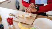 Mann schaut auf seine Fitnessuhr und bereitet Essen zu