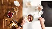 Sicht von oben auf einen Tisch: Mann bereitet Porridge zu