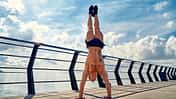 Ein trainierter Mann macht einen Handstand auf einem Schiffsdeck