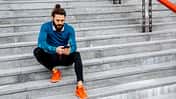 Mit seinem Smartphone nach dem Laufen auf einer Treppe
