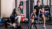Ein Mann trainiert mit einem Trainer an den Battle Ropes