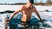Courageous man taking an ice bath in frozen lake during winter