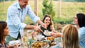 Lächelnde Freunde, die ein Mittagessen im Freien in einer mediterranen Umgebung genießen