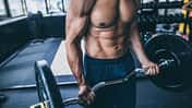 Muskulöser Mann trainiert mit Langhantel im Fitnessstudio