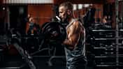 Muskulöser Mann im Fitnessstudio beim Langhantelheben Muskulöser Mann im Fitnessstudio beim Langhantelheben