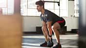 Mann macht eine Kniebeuge mit einem Kettleball