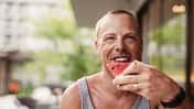 Ein Mann beißt glücklich in eine Wassermelone