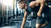 Ein trainierter Mann im Gym, der Rudern mit einer Kurzhantel an einer Bank macht