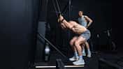 Zwei Männer trainieren im Fitnessstudio an einem SkiErgometer