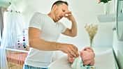 Vater wickelt sein Baby und hält sich die Nase zu