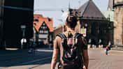 Ein junger Mann mit Rucksack spaziert durch die Straßen einer Altstadt