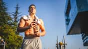 Ein trainierter, oberkörperfreier Mann hält einen Shaker in der Hand 
