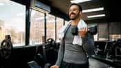 Junger Sportler, der mit Kurzhanteln im Fitnessstudio trainiert
