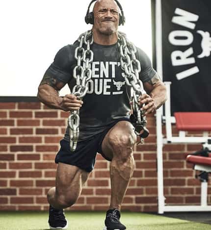 The Rock, Under Armour The Rock macht sichtlich angestrengt Ausfallschritte mit schweren Ketten auf den Schultern.